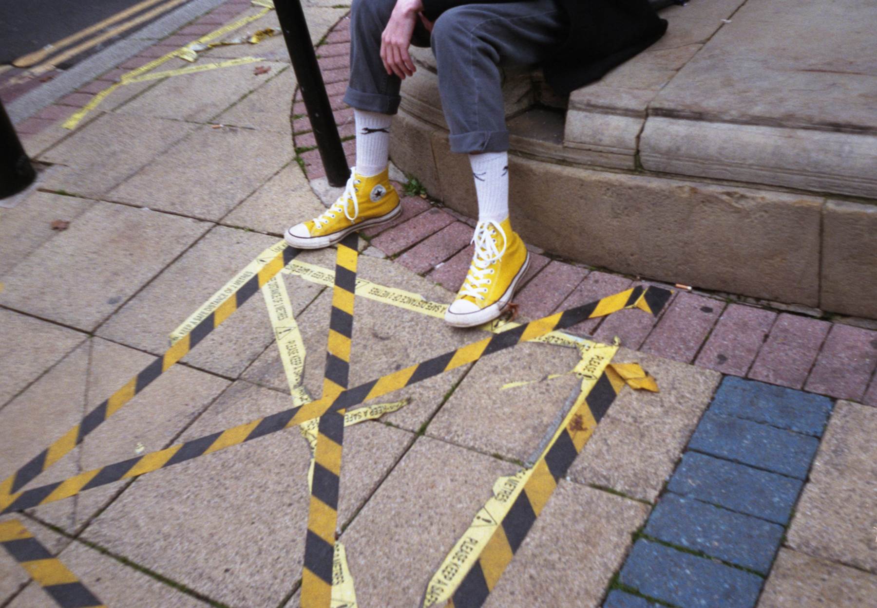 yellow converse trainers with yellow hazzard tape on ground