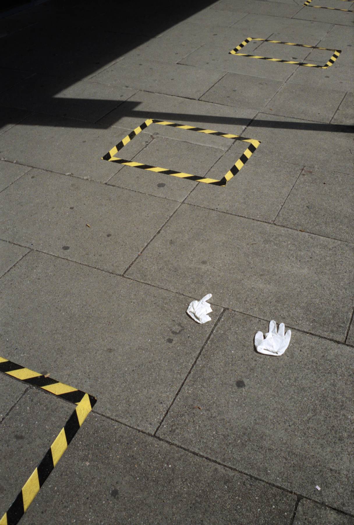 white gloves discarded on ground with hazzard tape on ground for queuing