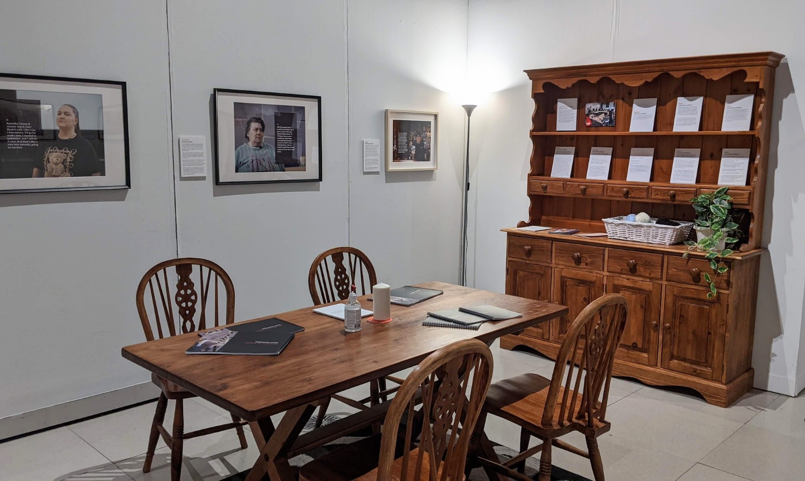 Dining room table with chairs, and a wall unit with surrounding pandemic stories and photobook on the table